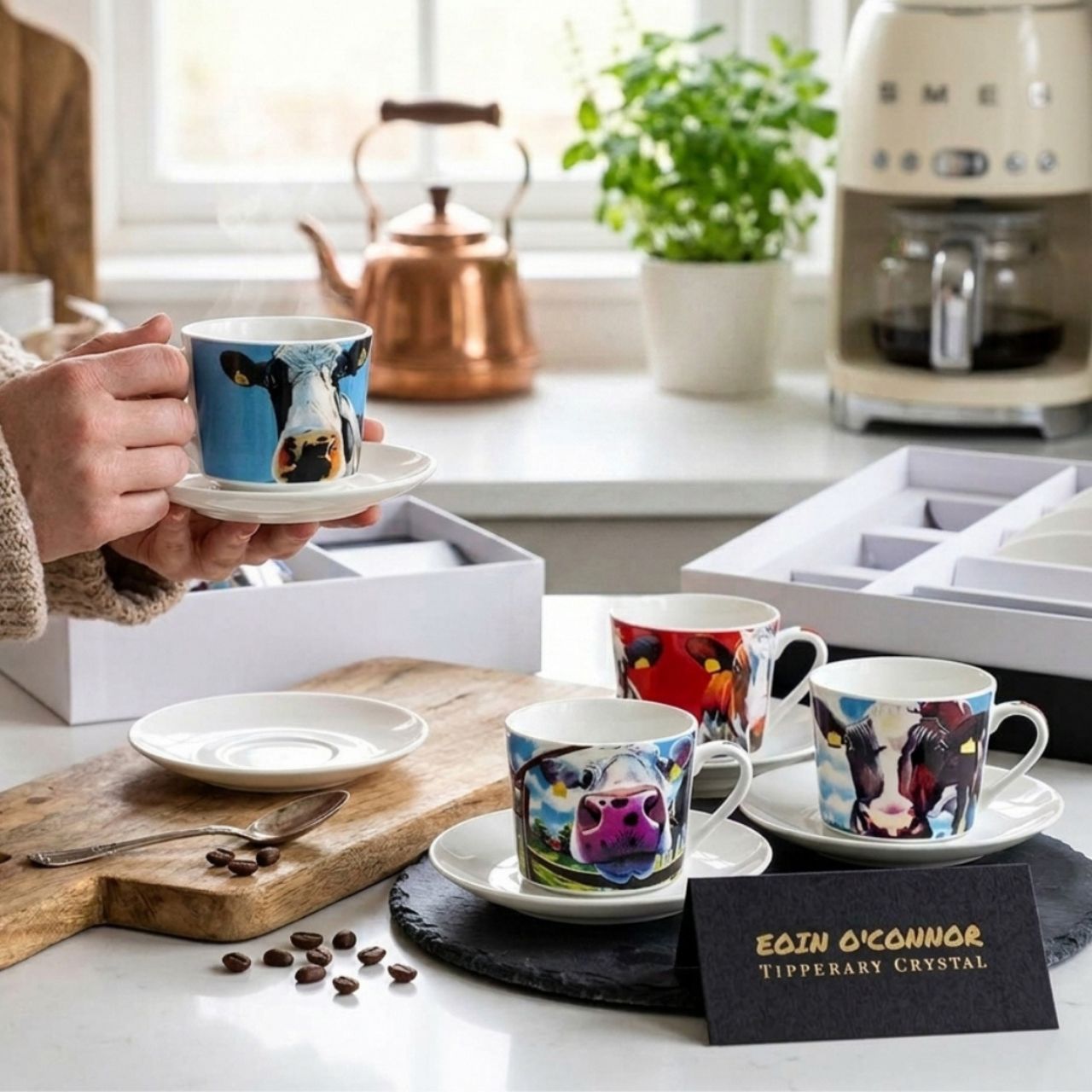 A fun set of four Egg Cup holders with Matching Spoons that have the Iconic Cow design from Eoin O'connor. Set of four New Bone China Egg Cups and four tea spoons in a gift box with cow print.