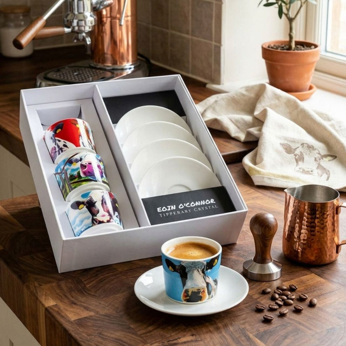 A fun set of four Egg Cup holders with Matching Spoons that have the Iconic Cow design from Eoin O'connor. Set of four New Bone China Egg Cups and four tea spoons in a gift box with cow print.