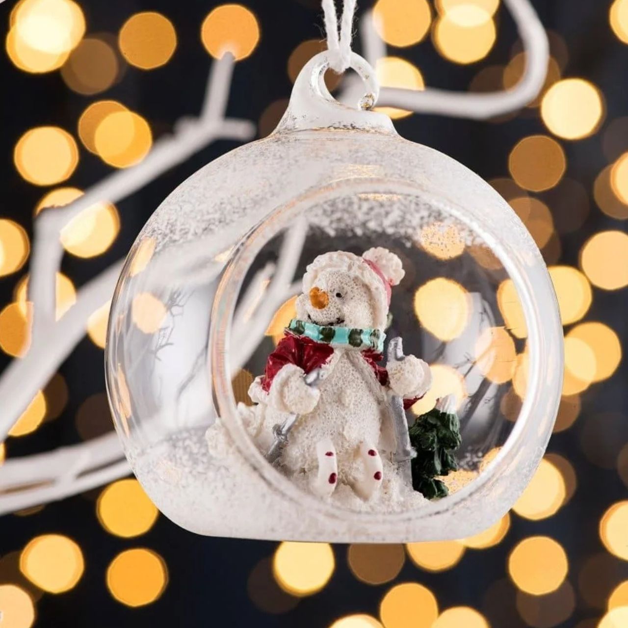 Take a peek into the world of this little Skiing Snowman. This frosted bauble displays a happy snowman skiing down a winter mountain. This hanging ornament is bound to stand out on your tree this year as the colours used are eye catching.&nbsp;
