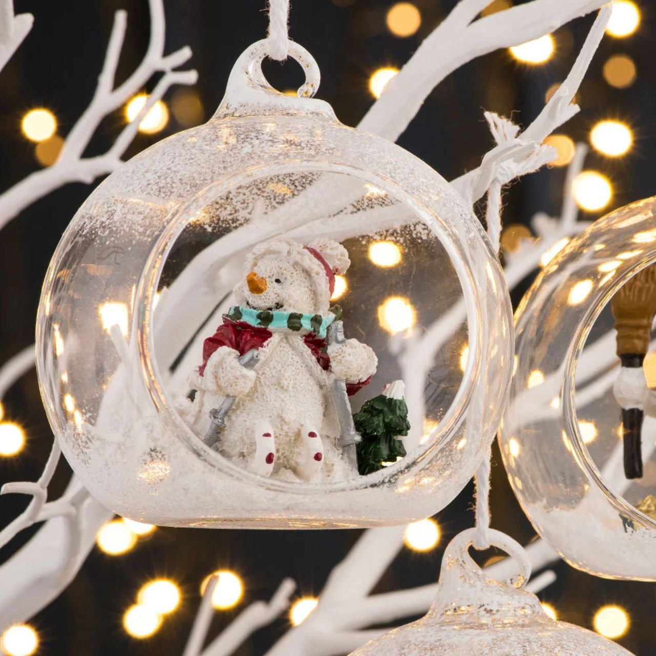 Take a peek into the world of this little Skiing Snowman. This frosted bauble displays a happy snowman skiing down a winter mountain. This hanging ornament is bound to stand out on your tree this year as the colours used are eye catching.&nbsp;