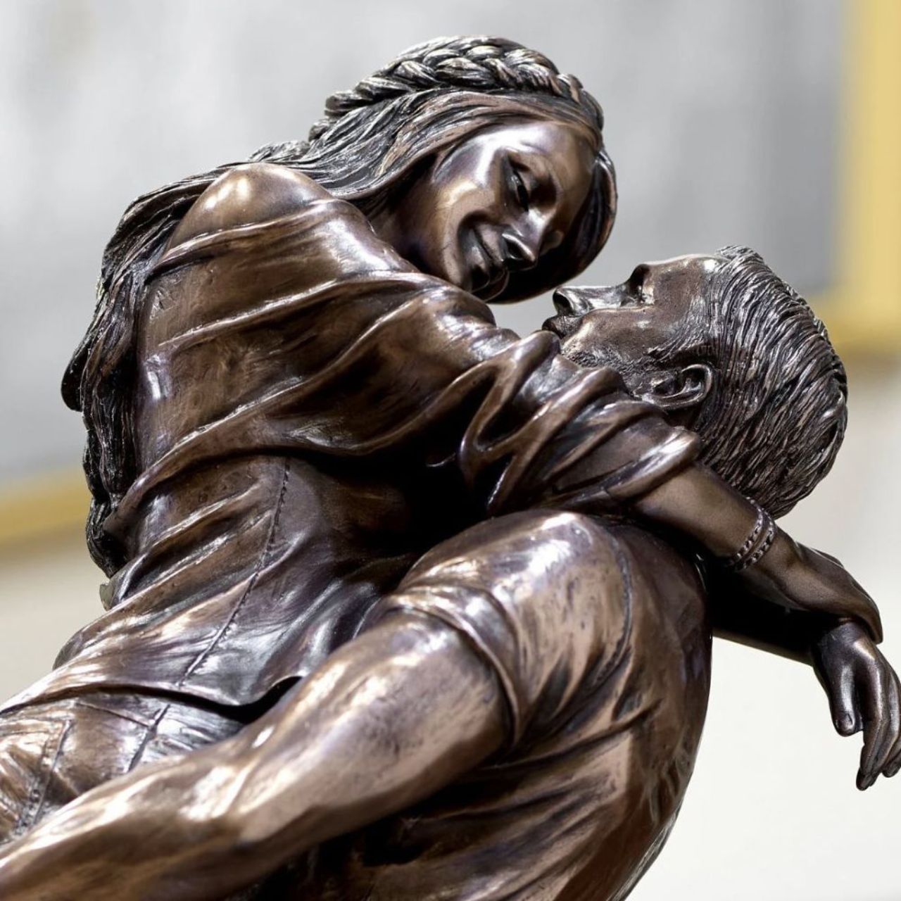 A beautiful bronze coloured statue of a couple in a loving embrace.