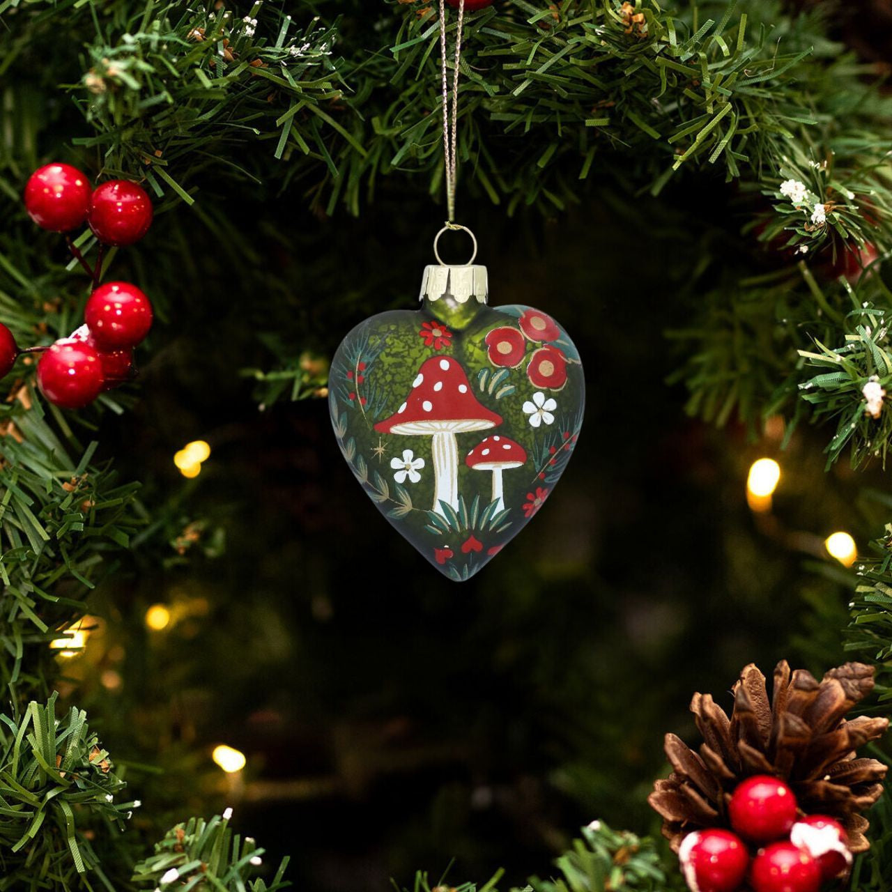Elevate your holiday decor with the Gisela Graham Glass Antique Green Heart Christmas Bauble. Featuring a delicate moss green heart adorned with charming toadstools, this elegant ornament adds a refined touch of nature-inspired beauty to your tree.