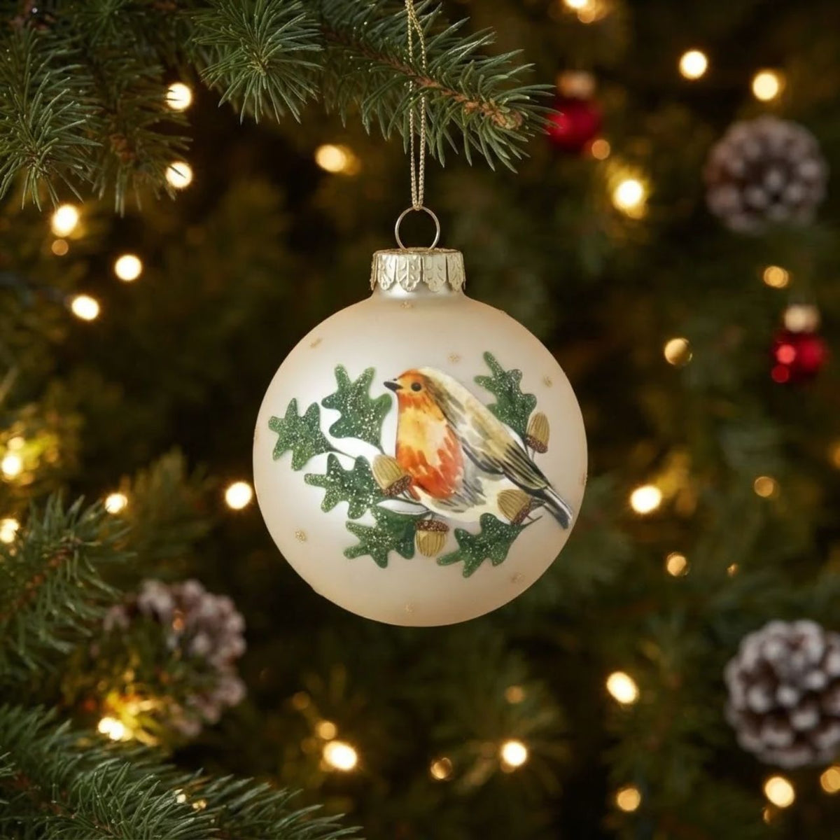 Elegant pale gold robin perched among delicate oak leaves, hand-painted on a premium glass bauble. This timeless Christmas ornament from Gisela Graham captures the beauty of winter wildlife with refined detail and a soft metallic finish.