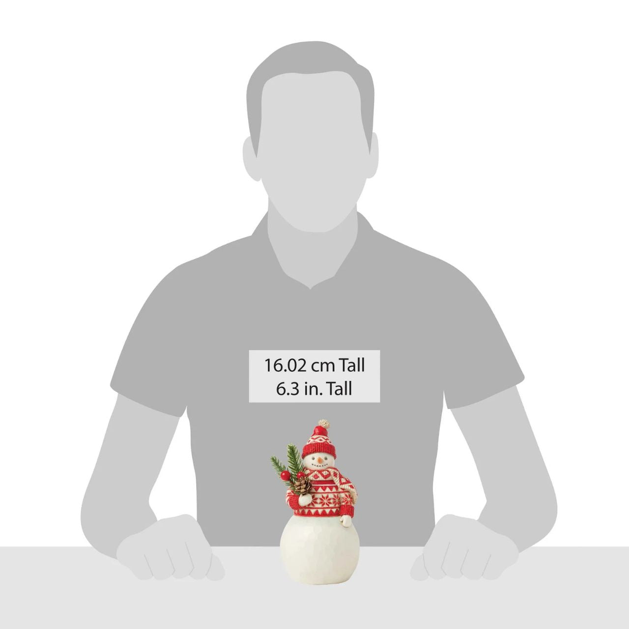 This cheerful Jim Shore Nordic Noel snowman is dressed in an intricately patterned red Nordic sweater, scarf, and hat, radiating warmth and holiday spirit. With a bright smile, he holds a fresh evergreen sprig in his hands, eagerly embracing the joys of Christmas.