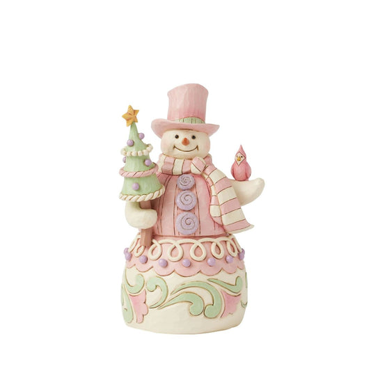 This whimsical Heartwood Sweets pastel pink snowman by Jim Shore radiates charm with his rosemaling patterns, sprinkles, and icing details, embodying the essence of holiday cheer. He lovingly holds a decorated tree and a cardinal.