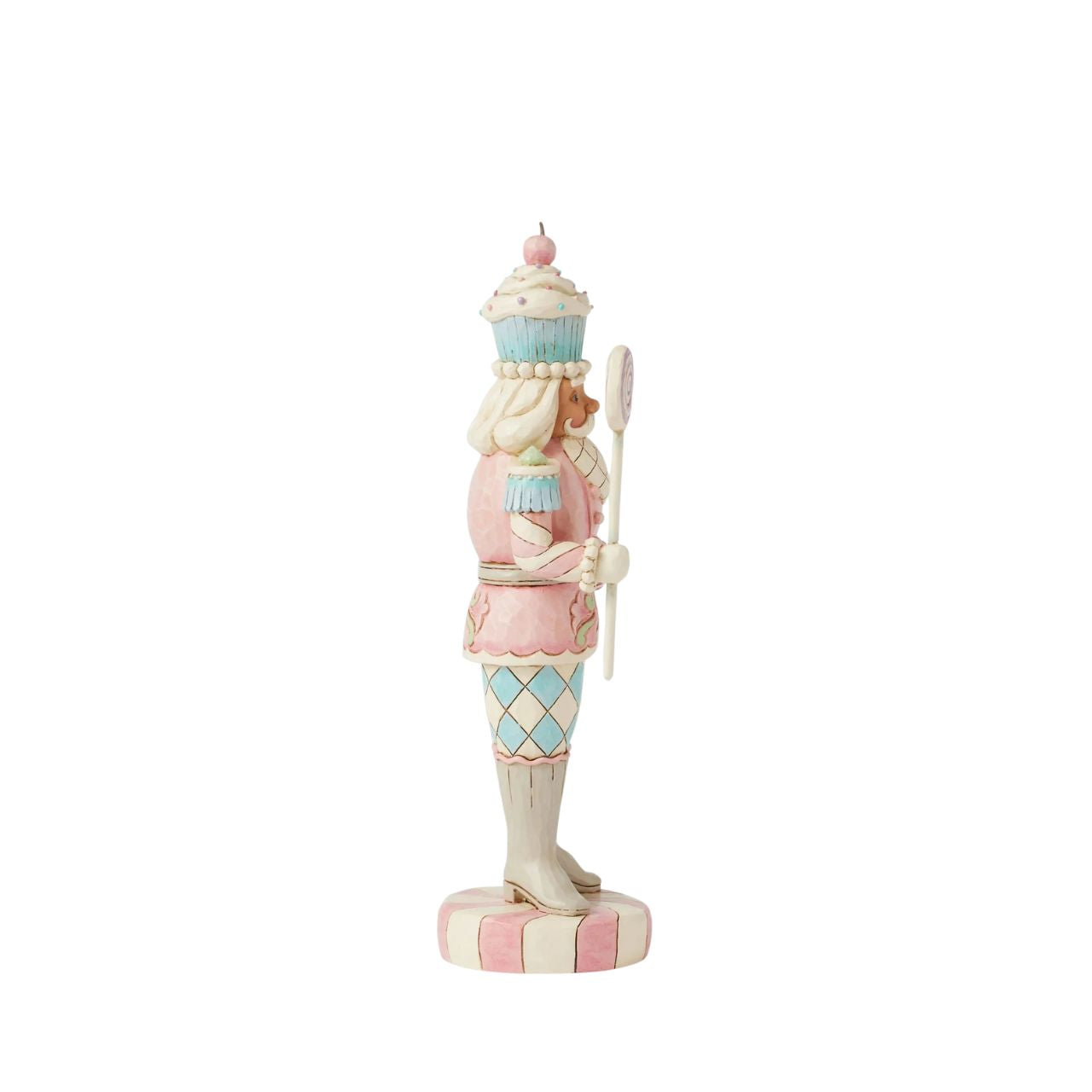 This Heartwood Sweets toy soldier design by Jim Shore stands proudly on a peppermint base, holding a lollipop staff. With a pastel-patterned uniform of icing and gumdrops, complete with a peppermint belt buckle and a delightful cupcake hat, he brings sweet presence to any holiday scene.