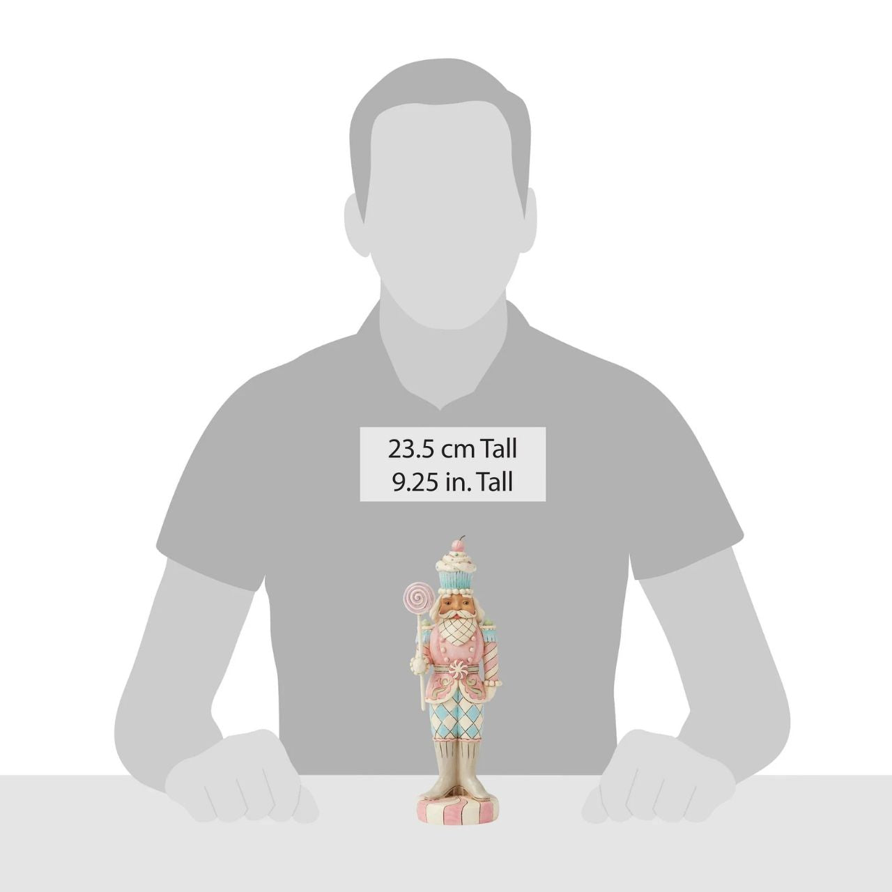 This Heartwood Sweets toy soldier design by Jim Shore stands proudly on a peppermint base, holding a lollipop staff. With a pastel-patterned uniform of icing and gumdrops, complete with a peppermint belt buckle and a delightful cupcake hat, he brings sweet presence to any holiday scene.