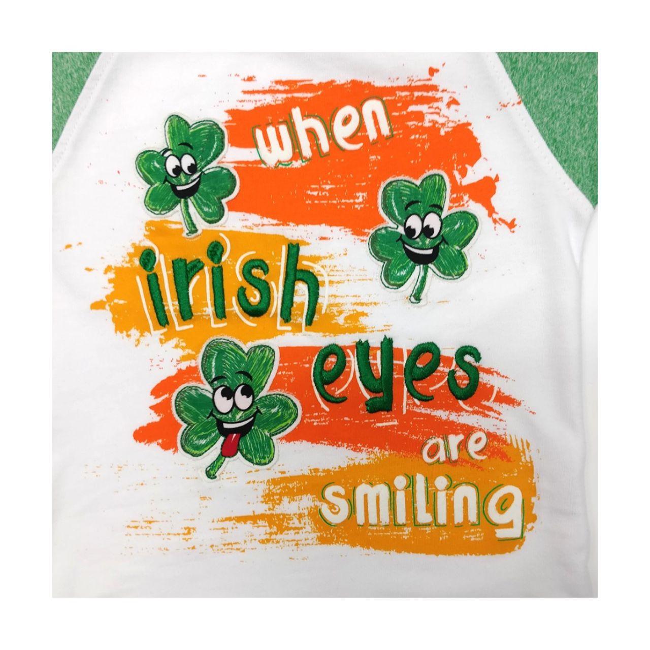 White & Green Grindle Irish Eyes Raglan Kids T-shirt  This white and green grindle kids T-shirt is part of the Traditional Craft Official Collection. This raglan style T-shirt is a relaxed fit and features embroidered shamrocks and wording over print. The classic phrase reads "When Irish eyes are smiling".