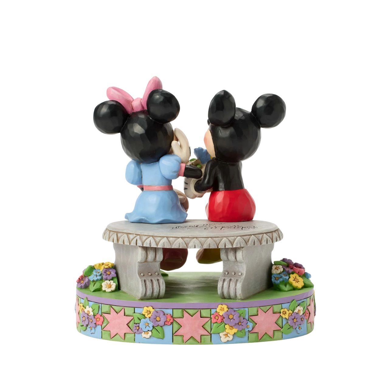Mickey and Minnie share a sweet moment on a park bench in this romantic Jim Shore scene. Surrounded by colourful flowers and Jim's rosemaling and quilt patterns, Mickey presents Minnie with a fresh bouquet as she blushes.
