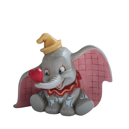 Disney Traditions A Gift of Love Dumbo with Heart Figurine  "A Gift of Love" Holding a heart with his trunk, the lovable flying elephant, Dumbo, smiles sweetly in this charming creation by Jim Shore. With pretty patchwork on his ears and rosemaled design on his skin, Dumbo looks dashing in this simple and sentimental design.