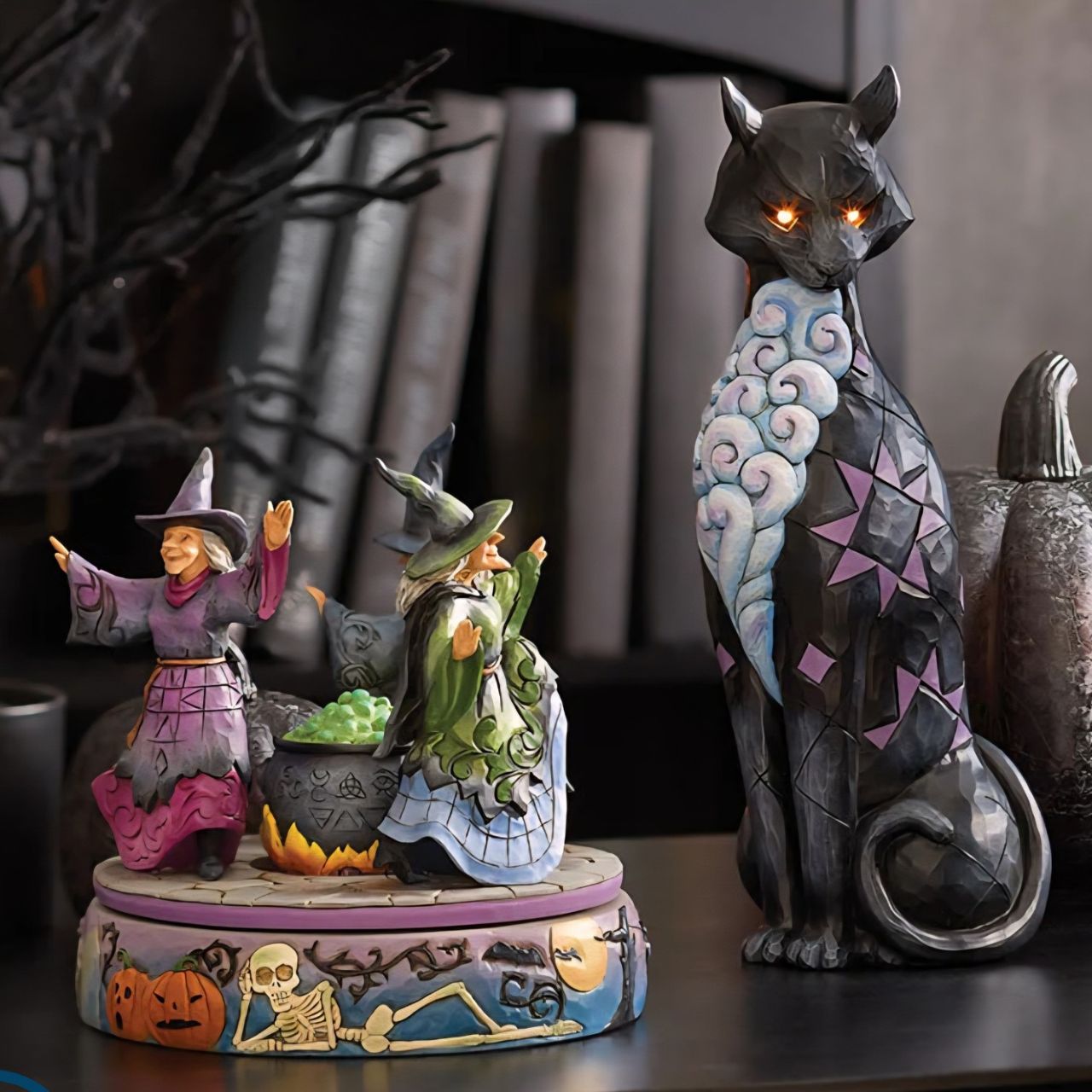 Enter the world of Halloween with this hand-touch rotation Jim Shore movement figurine featuring two witches dancing around a bubbling cauldron. Adorned with jack-o-lanterns, skeletons, tombstones, spiders, snakes, black cats, and bats, it's a bewitching scene.
