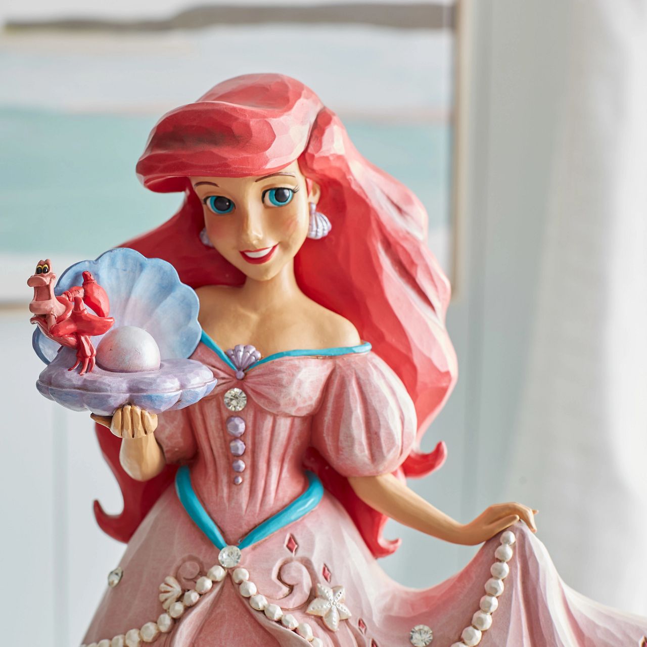 "A Precious Pearl" Second in the Series of Deluxe Figurines, The Enchanted Princess Series, is this striking 40cm Ariel Figurine. Thanks to the magic of a mysterious sea witch, Ariel The Little Mermaid, grows legs to walk on land. This sparkling Jim Shore figurine features the princess at her prettiest, her gown fitted with shells and jewels, she holds an oyster with a pearl.