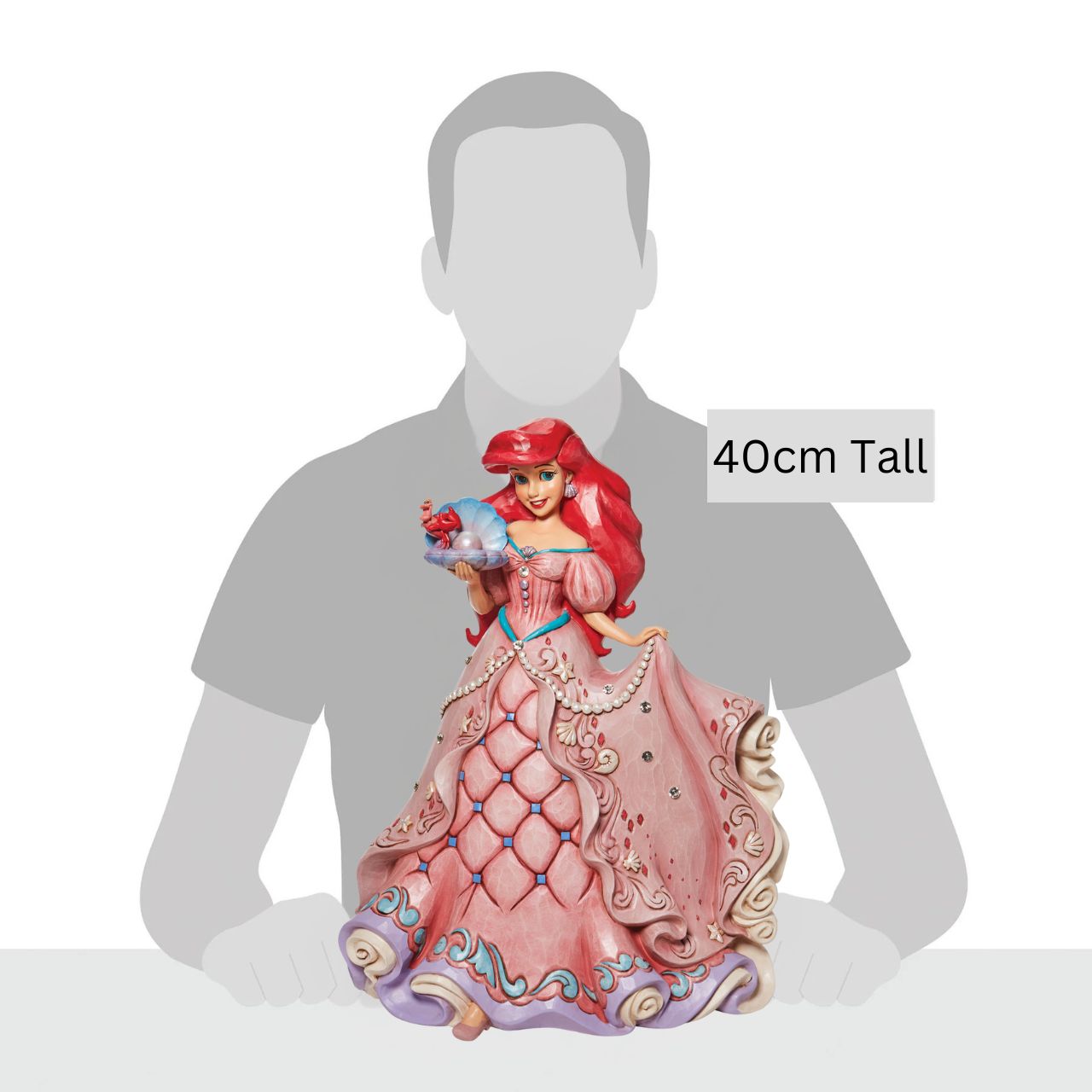 "A Precious Pearl" Second in the Series of Deluxe Figurines, The Enchanted Princess Series, is this striking 40cm Ariel Figurine. Thanks to the magic of a mysterious sea witch, Ariel The Little Mermaid, grows legs to walk on land. This sparkling Jim Shore figurine features the princess at her prettiest, her gown fitted with shells and jewels, she holds an oyster with a pearl.