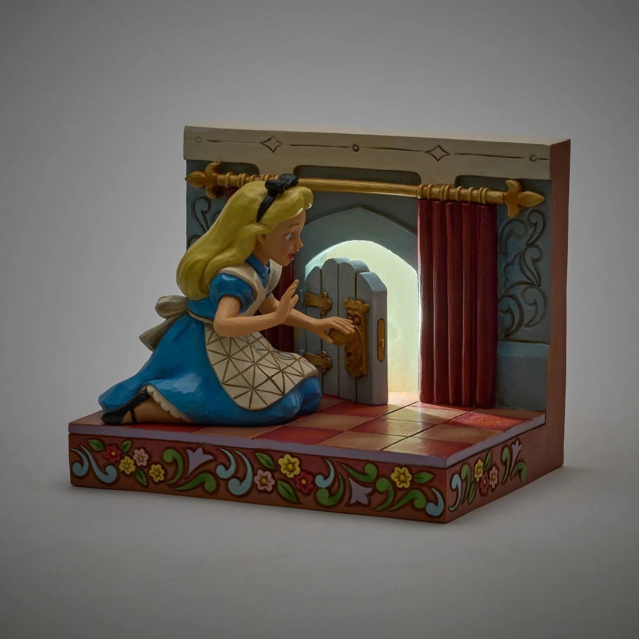 Alice eagerly opens the door to Wonderland, twisting the smiling doorknob while the curtains draw back to reveal the enchanting realm beyond. With inviting LED lights, this captivating Jim Shore scene captures the curiosity of Alice's adventure.