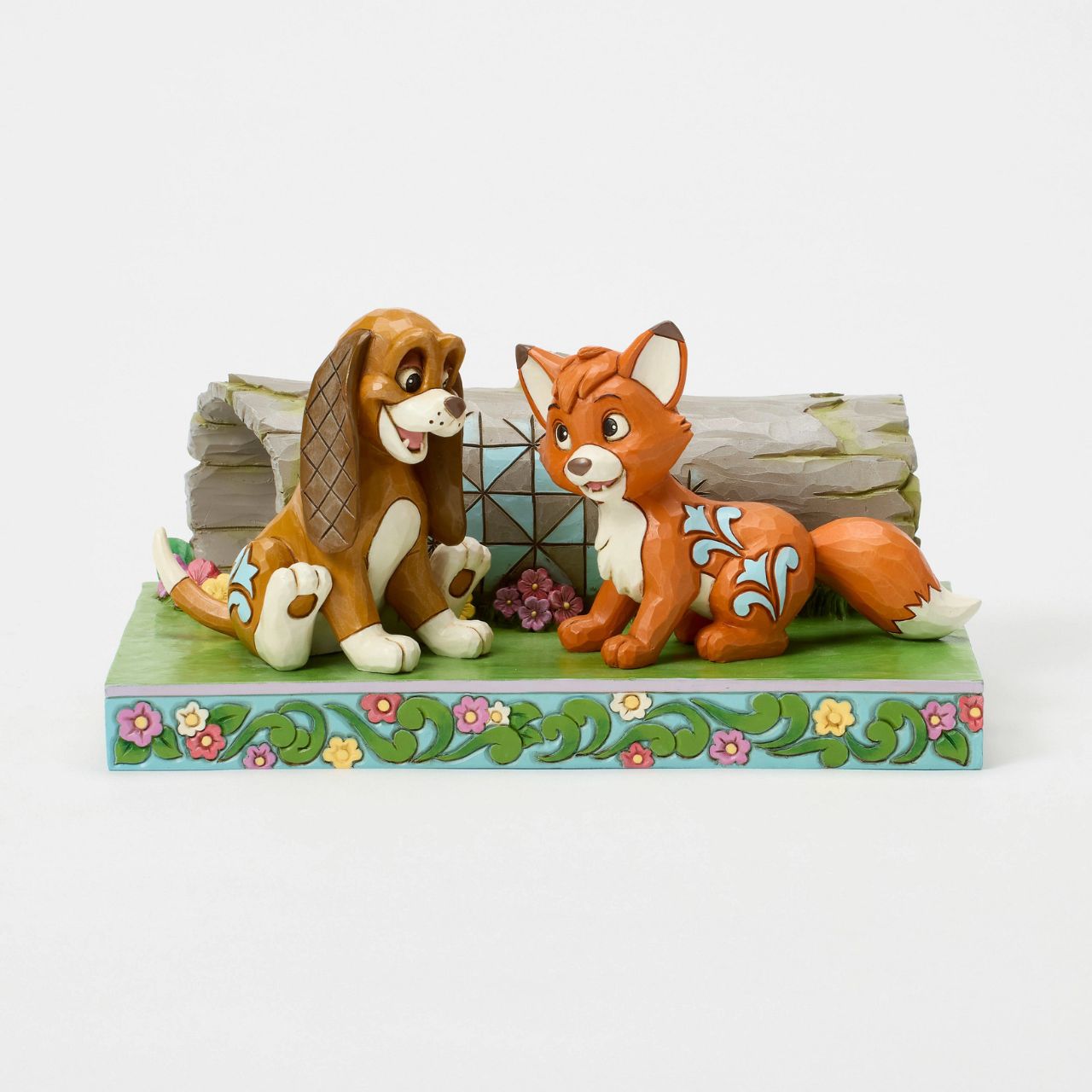 Celebrate the unlikely friendship between Fox and the Hound in this charming Jim Shore scene. As they play in the woods, Jim Shore's iconic rosemaling, patchwork patterns, and floral details bring the vibrant scene to life.