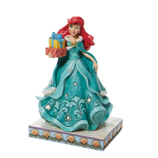 Jim Shore Ariel Little Mermaid with Gifts Figurine - Gifts of Song  In a brilliant blue dress, Ariel is a vision of beauty and gratitude in this lovely Jim Shore statuette. Carrying gifts and wearing a broach of holly, the princess delivers presents to all those Under the Sea. Flounder and Sebastian grace the base. Hand painted and hand sculpted from high quality cast stone.