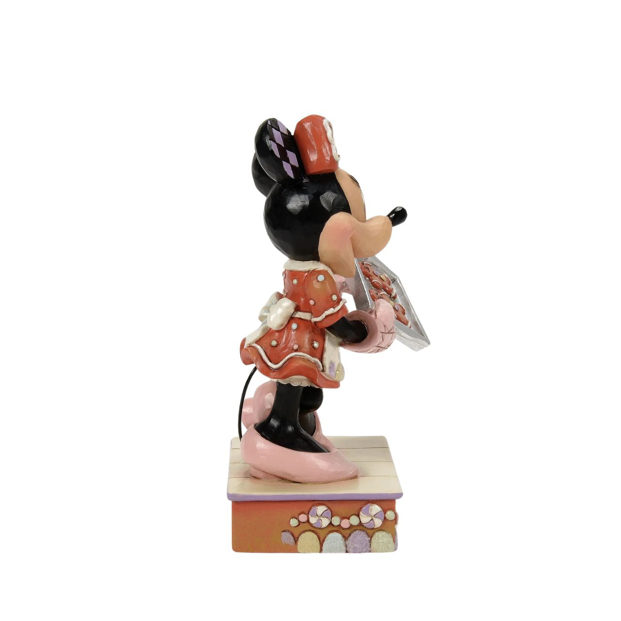 Dressed in a delightful gingerbread-inspired dress and bow, Minnie Mouse shares freshly baked cookies in this heartwarming Jim Shore scene. Standing on a stage of colourful candy, Minnie brings the warmth and sweetness of the season to life.