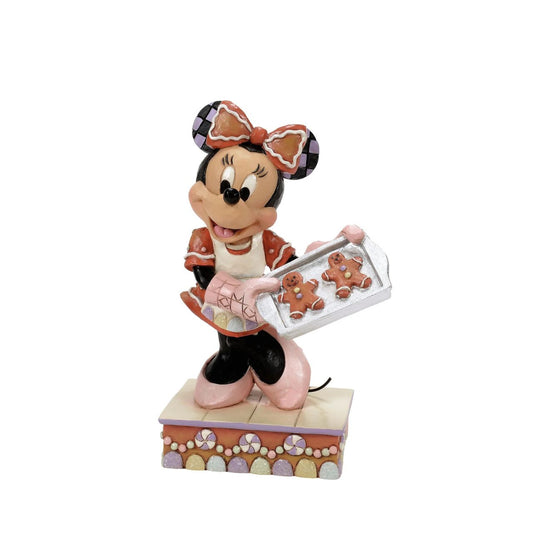 Dressed in a delightful gingerbread-inspired dress and bow, Minnie Mouse shares freshly baked cookies in this heartwarming Jim Shore scene. Standing on a stage of colourful candy, Minnie brings the warmth and sweetness of the season to life.
