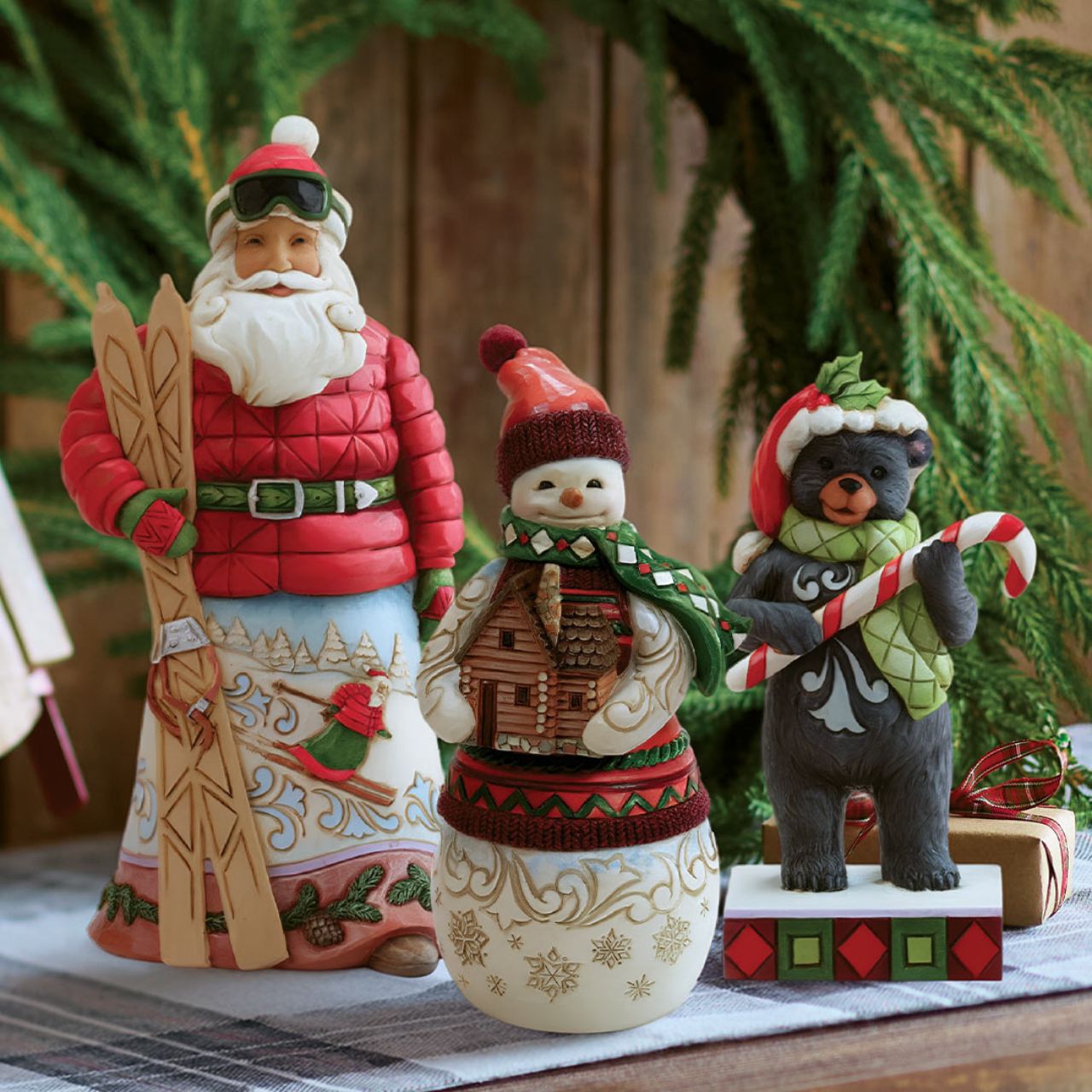 This playful Christmas at the Lodge Jim Shore black bear wears a festive Santa hat adorned with holly, he wears a festive scarf and holds a candy cane in his paws. With rosemaling designs on his fur, the piece brings sweet holiday fun and rustic charm to to any display.