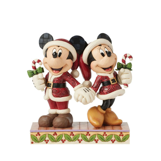In this festive Jim Shore scene, Mickey and Minnie Mouse don Santa suits adorned with intricate rosemaling patterns and joyfully carry candy canes. Their bright smiles radiate holiday cheer, making the scene a delightful celebration of the season.