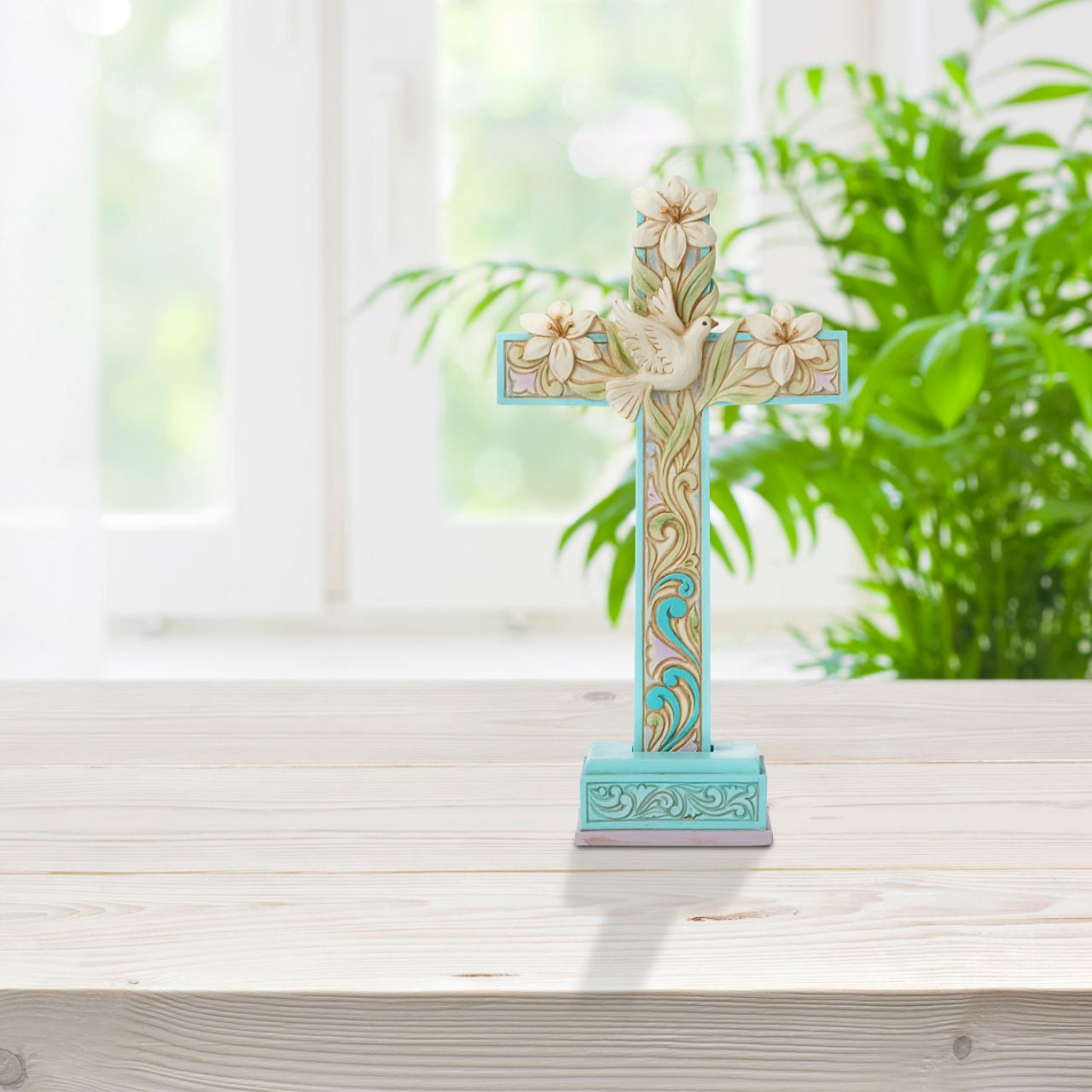 Cross with Lilies and Dove Figurine by Jim Shore  Brandished in Easter lilies, this cool blue and purple Jim Shore cross hosts intertwining vines of promise and serenity. A beautiful white dove sits in the centre of the crucifix, symbolizing the peace and promise of new life delivered by Jesus' resurrection.