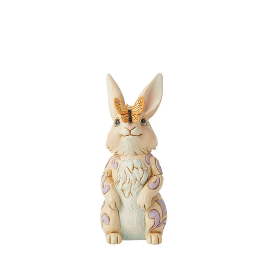 Enchanted by a butterfly resting on its nose, this adorable mini bunny stands tall with gentle sincerity. With delicate purple rosemaling on his fur, this Jim Shore rabbit figurine is sure to inspire smiles this Spring.