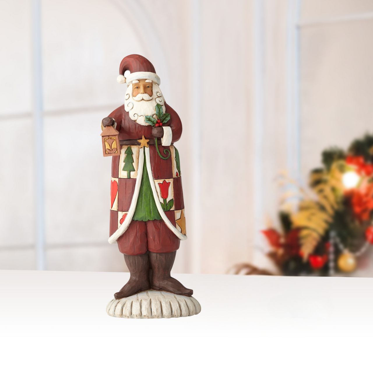 Heartwood Creek Folklore Santa With Lantern  The Folklore collection features Jim Shore's signature colour palette and heartfelt, rustic design. Cloaked in a charming patchwork of quaint holiday symbols, this handcrafted Santa holds a traditional lantern and cheery sprig of holly.