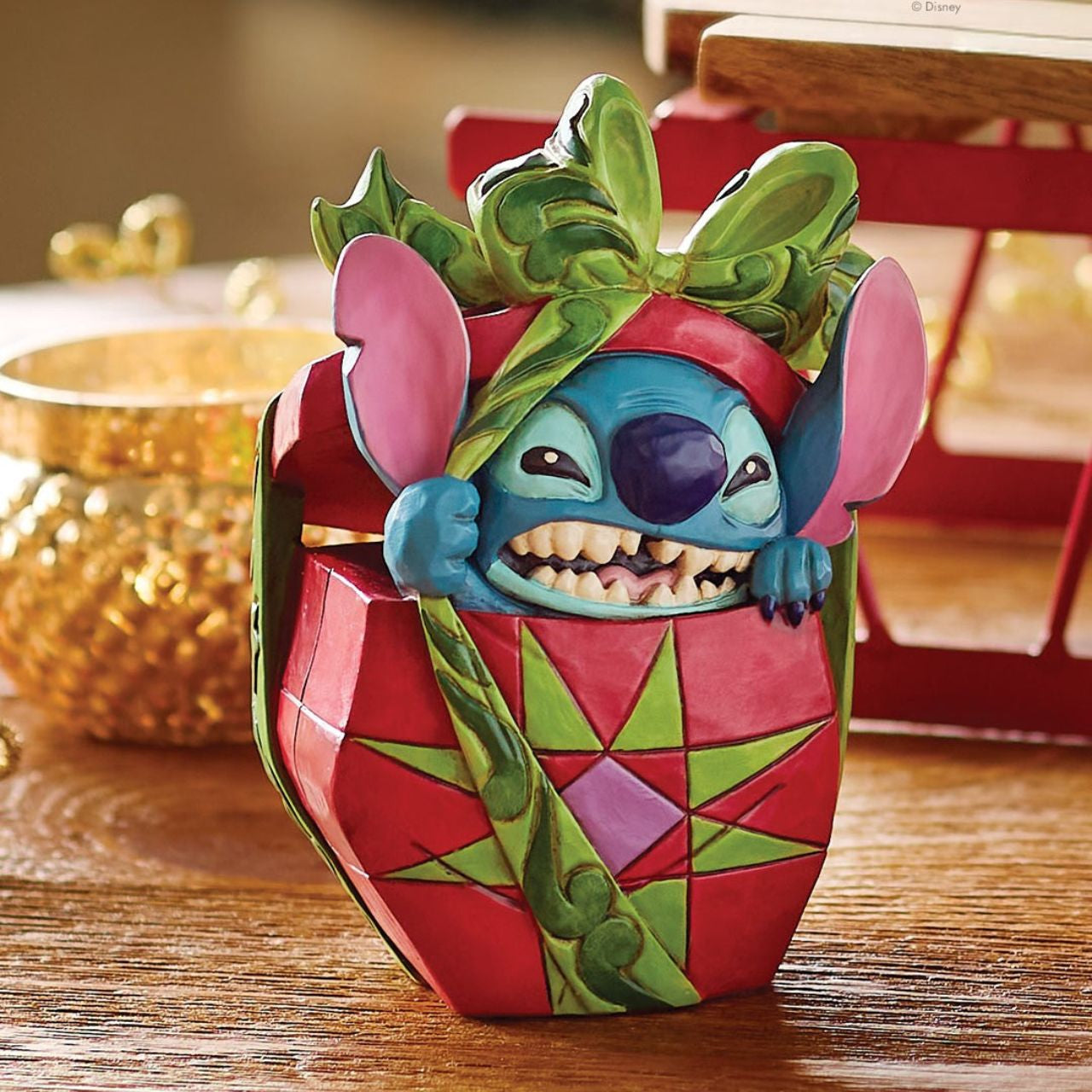 In this playful Jim Shore design, Stitch the alien bursts out of a vibrant Christmas present, showcasing his mischievous grin as he tears through festive wrapping. With his joyful chaos, Stitch proves that his lively presence is the best gift of all.