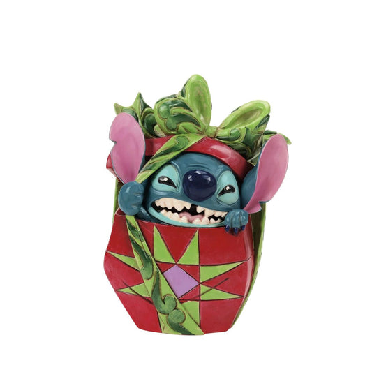 In this playful Jim Shore design, Stitch the alien bursts out of a vibrant Christmas present, showcasing his mischievous grin as he tears through festive wrapping. With his joyful chaos, Stitch proves that his lively presence is the best gift of all.