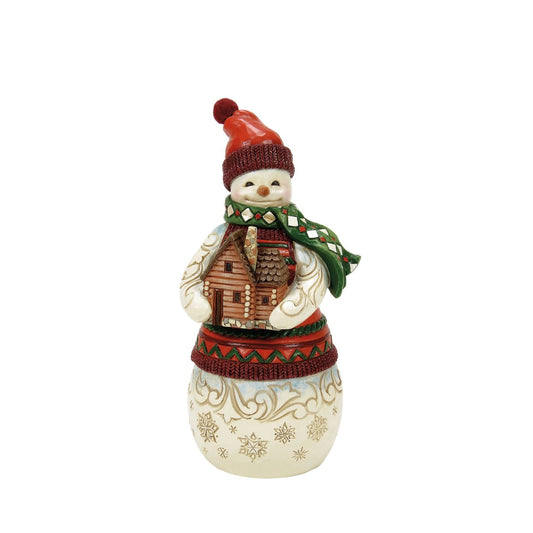 This Christmas at the Lodge Jim Shore snowman is dressed in an intricate red and green tunic and holds a little log cabin. With a knit cap, rosy cheeks, and a joyful smile, he glows with rosemaling and snowflakes, bringing festive warmth and cosy cabin vibes.
