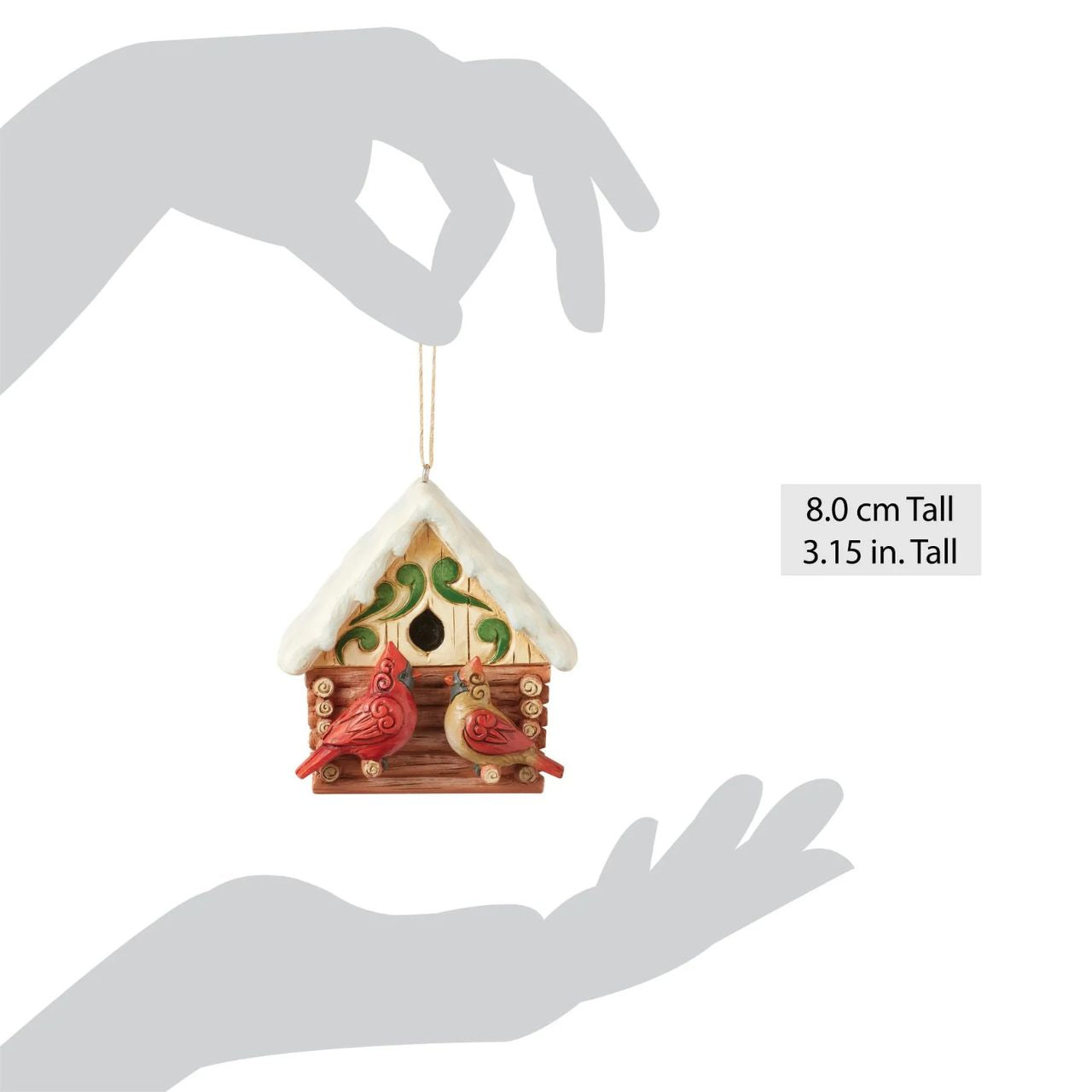 This Christmas at the Lodge enchanting Jim Shore ornament showcases a charming birdhouse designed to resemble a miniature log cabin, complete with Jim Shore's iconic rosemaling. Perched are a pair vibrant cardinals that add a touch of love.