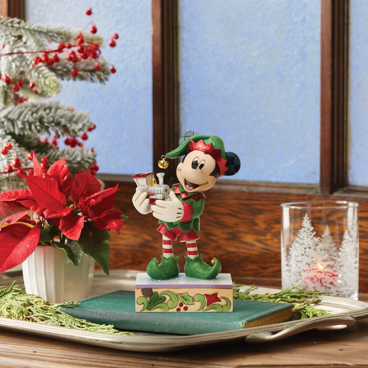 Mickey is Santa's helper as he hand delivers a festive toy train in this Special Edition Jim Shore holiday bust. Featuring bright folk art details and a sparkling gem on the engine, Mickey the elf brings holiday wonder to any Christmas display.