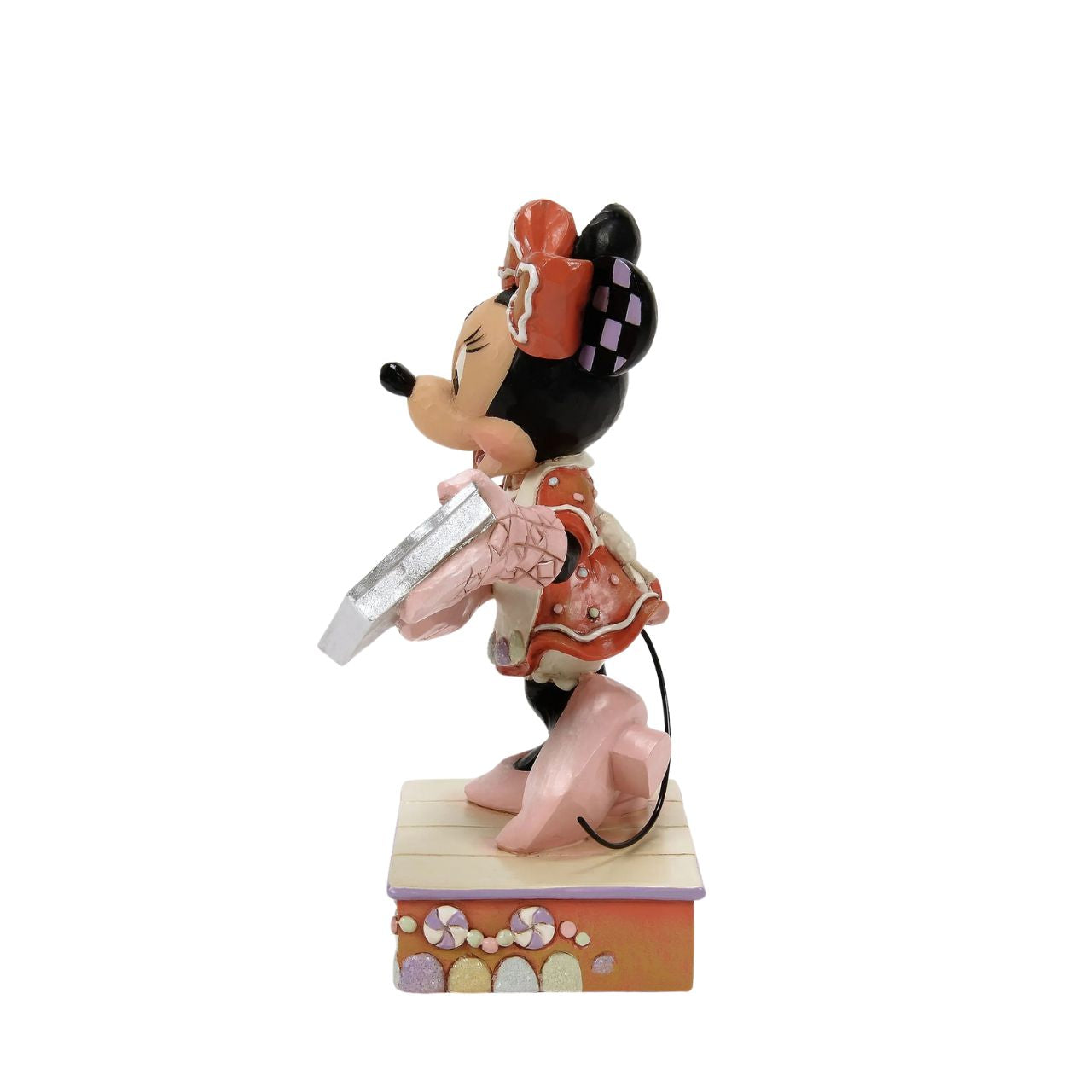 Dressed in a delightful gingerbread-inspired dress and bow, Minnie Mouse shares freshly baked cookies in this heartwarming Jim Shore scene. Standing on a stage of colourful candy, Minnie brings the warmth and sweetness of the season to life.