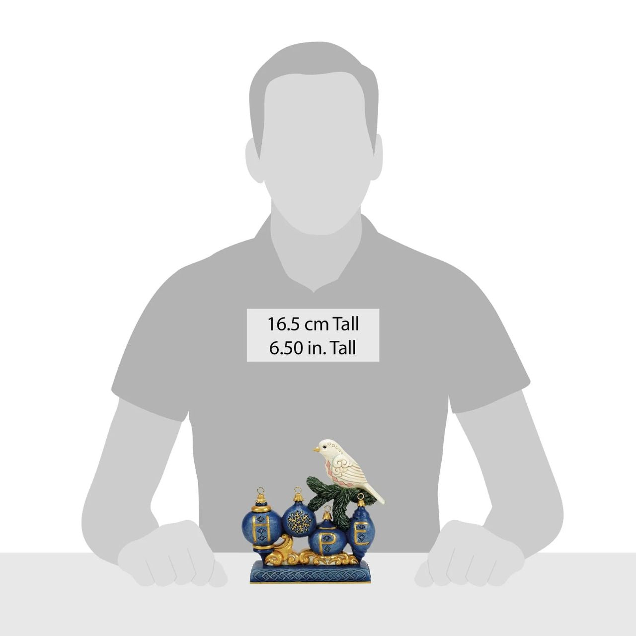 This elegant Jim Shore ornament features a beautifully patterned dove resting on a pine sprig, with a blue ornament adorned with a golden snowflake hanging gracefully below. The rich colours and details bring a sense of peace to your holiday home.