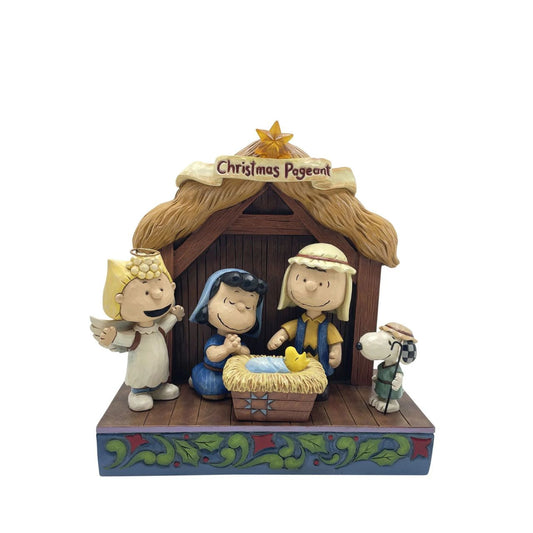 Jim Shore invites you to the Peanuts Christmas pageant! On a rosemale stage, Lucy and Linus sit in a manger dressed as Mary and Joseph tending to a Woodstock baby Jesus. Sally is dressed as an angel and Snoopy is a shepherd.