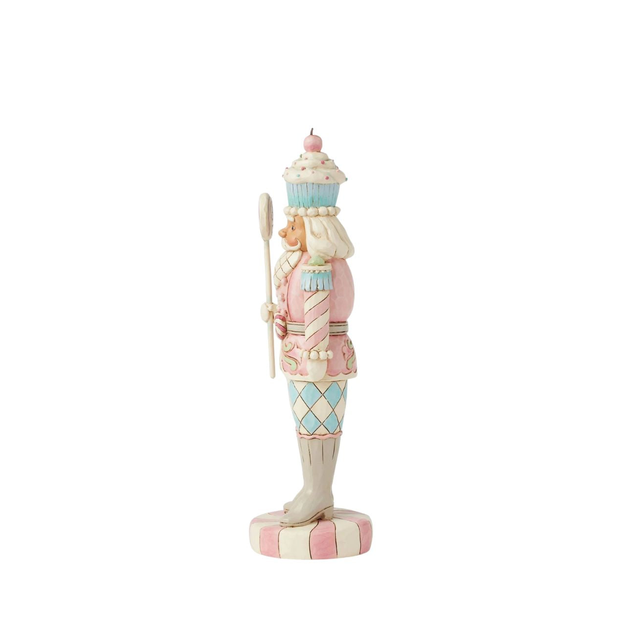 This Heartwood Sweets toy soldier design by Jim Shore stands proudly on a peppermint base, holding a lollipop staff. With a pastel-patterned uniform of icing and gumdrops, complete with a peppermint belt buckle and a delightful cupcake hat, he brings sweet presence to any holiday scene.