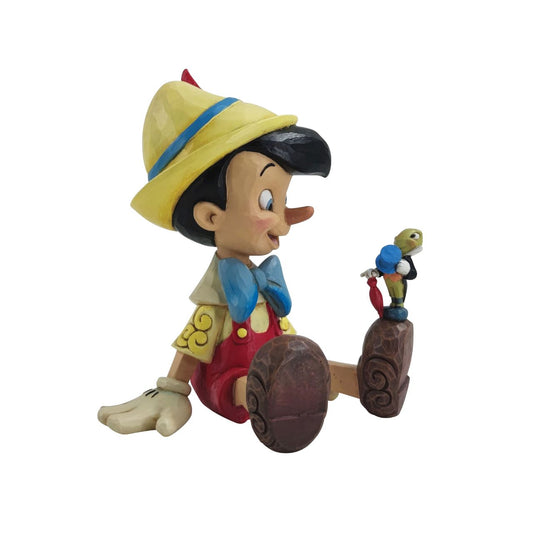 Pinocchio and Jiminy Sitting Figurine by Jim Shore  "Wishful and Wise" Jiminy Cricket is quite the dapper conscience in this design by Jim Shore, giving a tip o' his top hat as he smiles and gives his bestie Pinocchio a lesson about temptations.