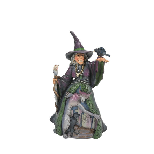 Enter the enchanting world of Halloween with this haunting Jim Shore witch figurine, adorned in ghastly purple and green robes, a perched crow and a staff with a slithering snake. Her cloak reveals a chilling graveyard scene with a spook and a black cat.