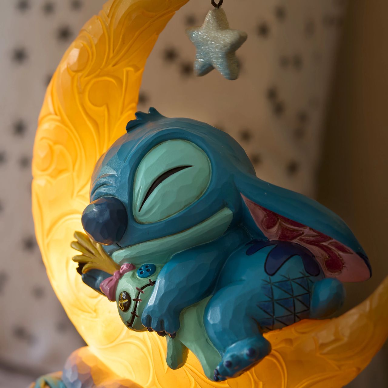 Snuggled up with his plush Scrump, Disney's Stitch is ready for dreamland. Asleep on a crescent moon that glows, this is the perfect addition to any display or bedroom. Requires 3x AAA batteries (not included), uses an automatic timer for 6 hours on, 18 hours off.