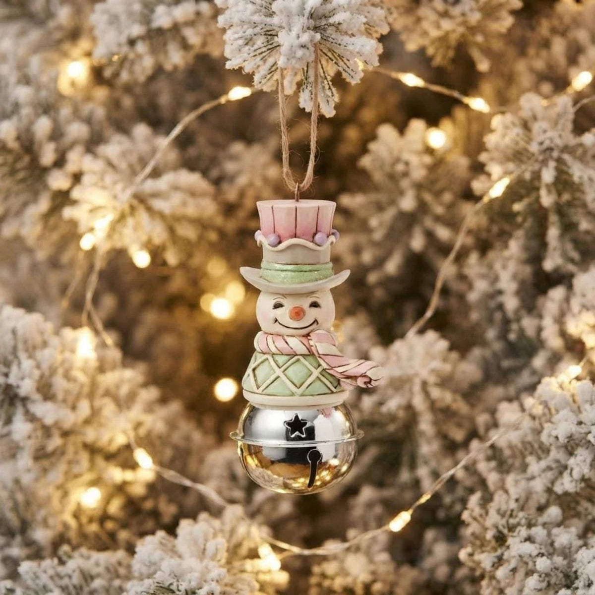 This delightful Jim Shore Heartwood Sweets jingle bell ornament features a charming miniature bust of a snowman, smiling in pastel decor, his vest is decorated with festive gumdrops. Ring in the season with Jim Shore.