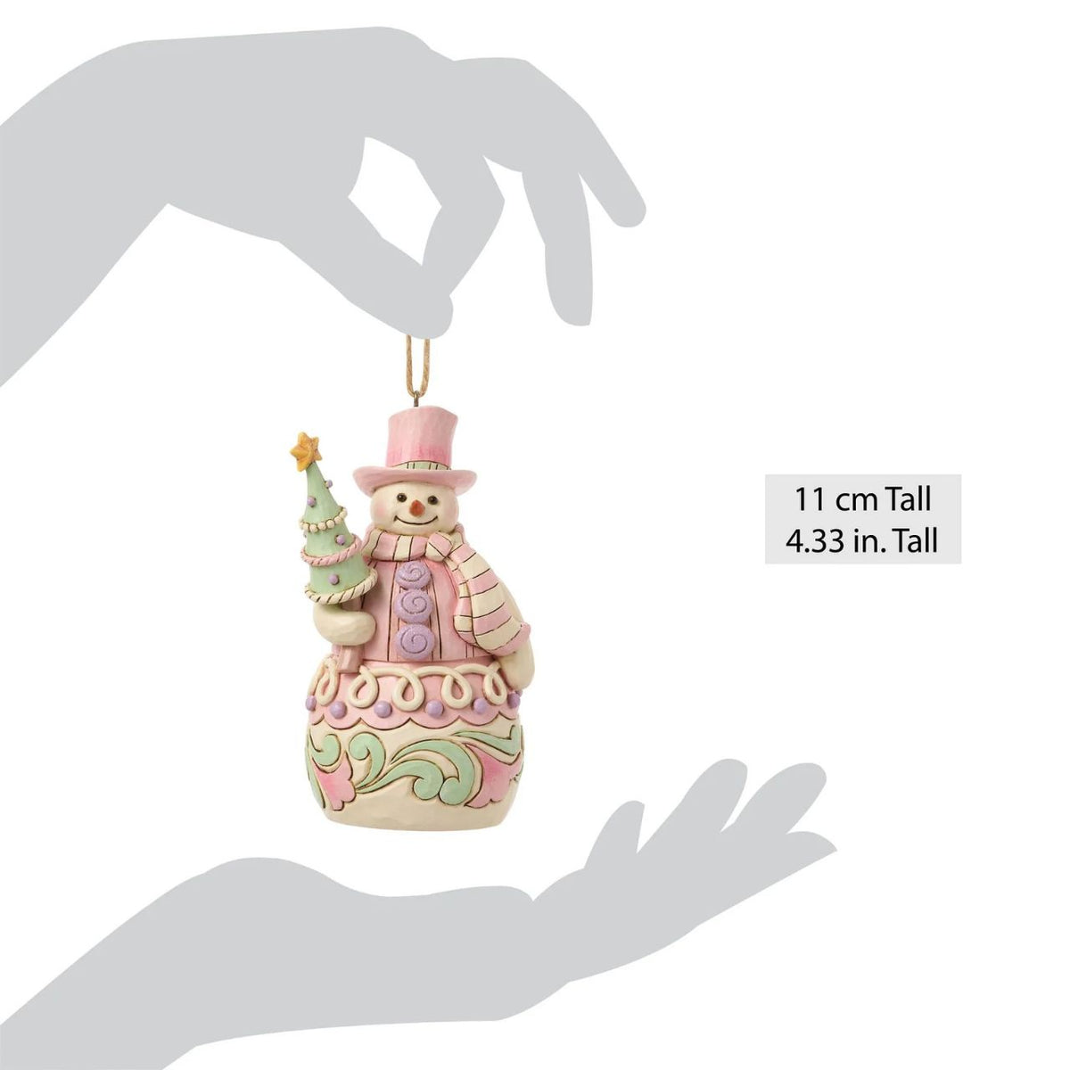 Bundled up for the season, this snowman ornament carries a decorated Christmas tree in his arms. Jim Shore's intricate designs swirl across his coat, adding heart-warming detail to this classic winter character. A joyful symbol of holiday sweetness.