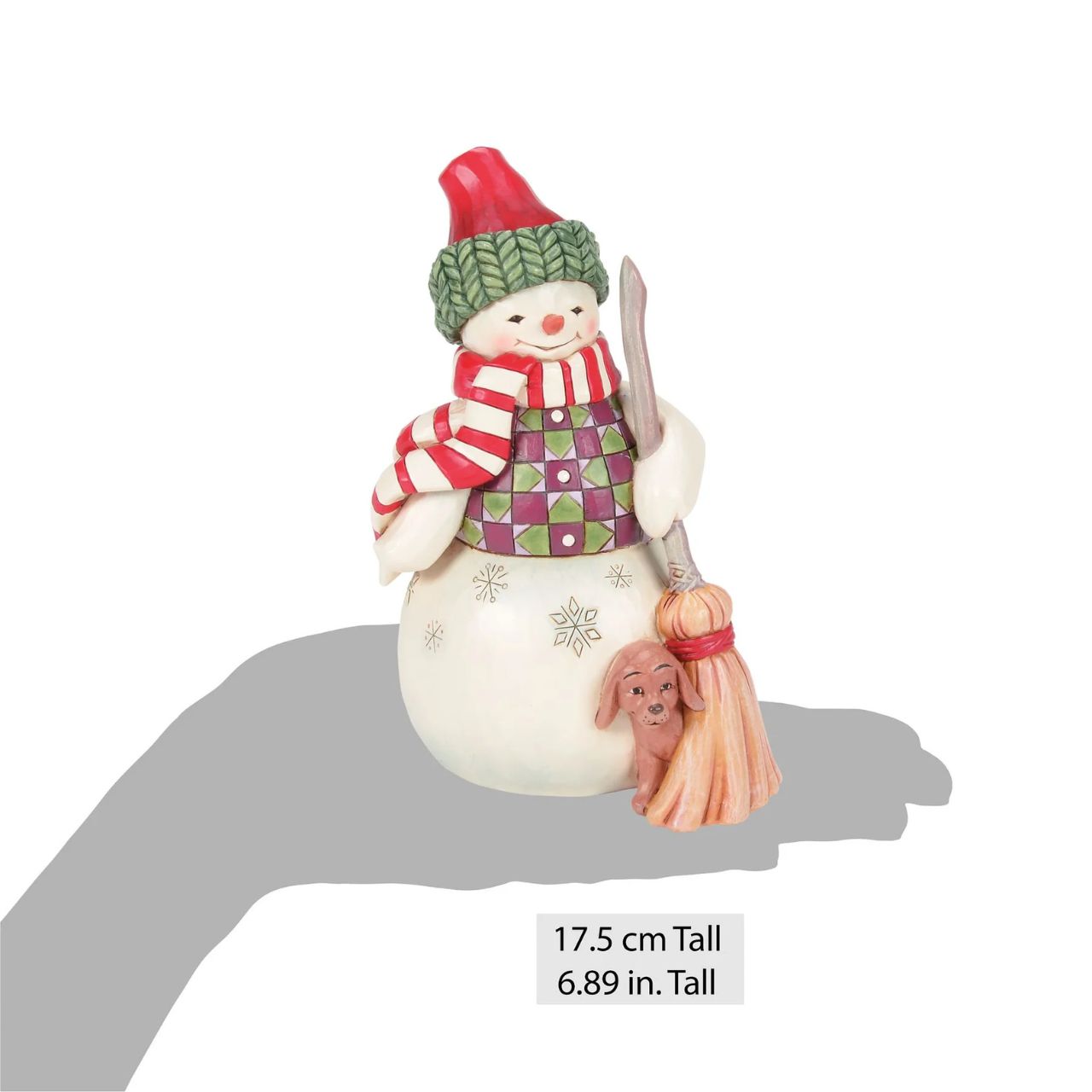 This Jim Shore snowman is dressed in a patterned tunic and holds a broom, and is accompanied by a precious pup peeking out with an excitable spirit. Together, they embody the joy of the season, spreading smiles and warmth through the snowy landscape.