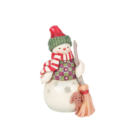 This Jim Shore snowman is dressed in a patterned tunic and holds a broom, and is accompanied by a precious pup peeking out with an excitable spirit. Together, they embody the joy of the season, spreading smiles and warmth through the snowy landscape.