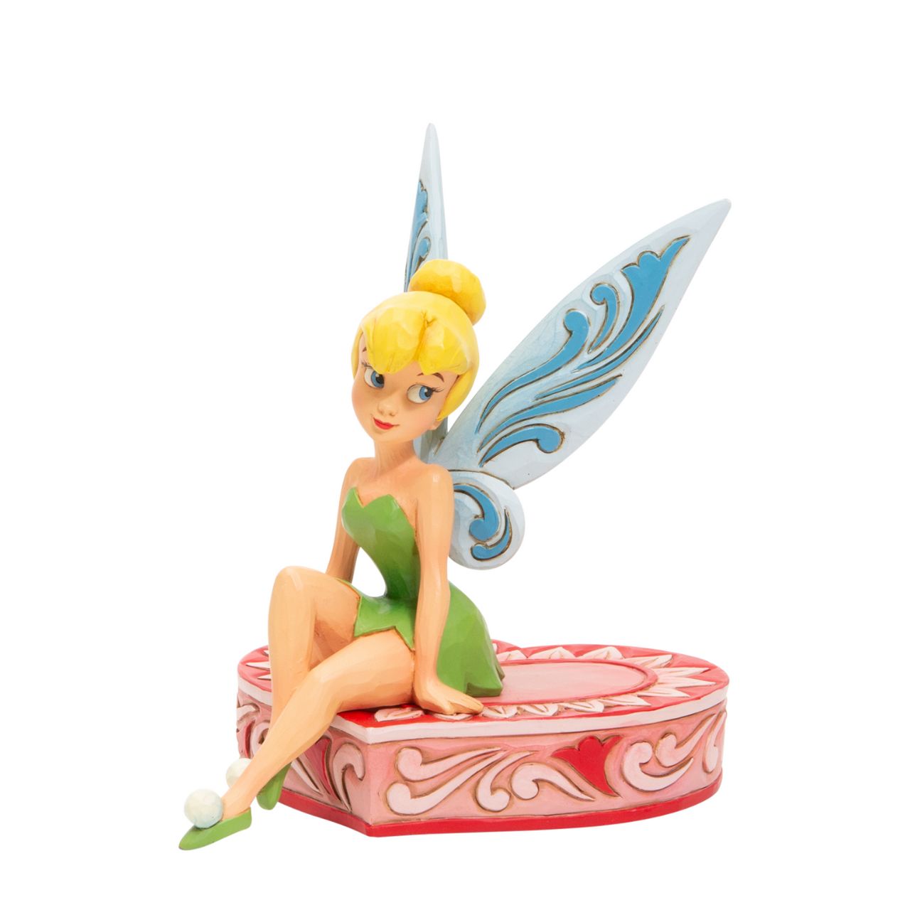 This fairy is sweeter than candy and sits on a heart-shaped box in this Jim Shore collectible. Tinkerbell, Peter Pan's sassy sidekick smiles coquettishly legs crossed daintily. With delicate rosemaling this fairy is in the love seat. Unique variations should be expected as this product is hand painted.