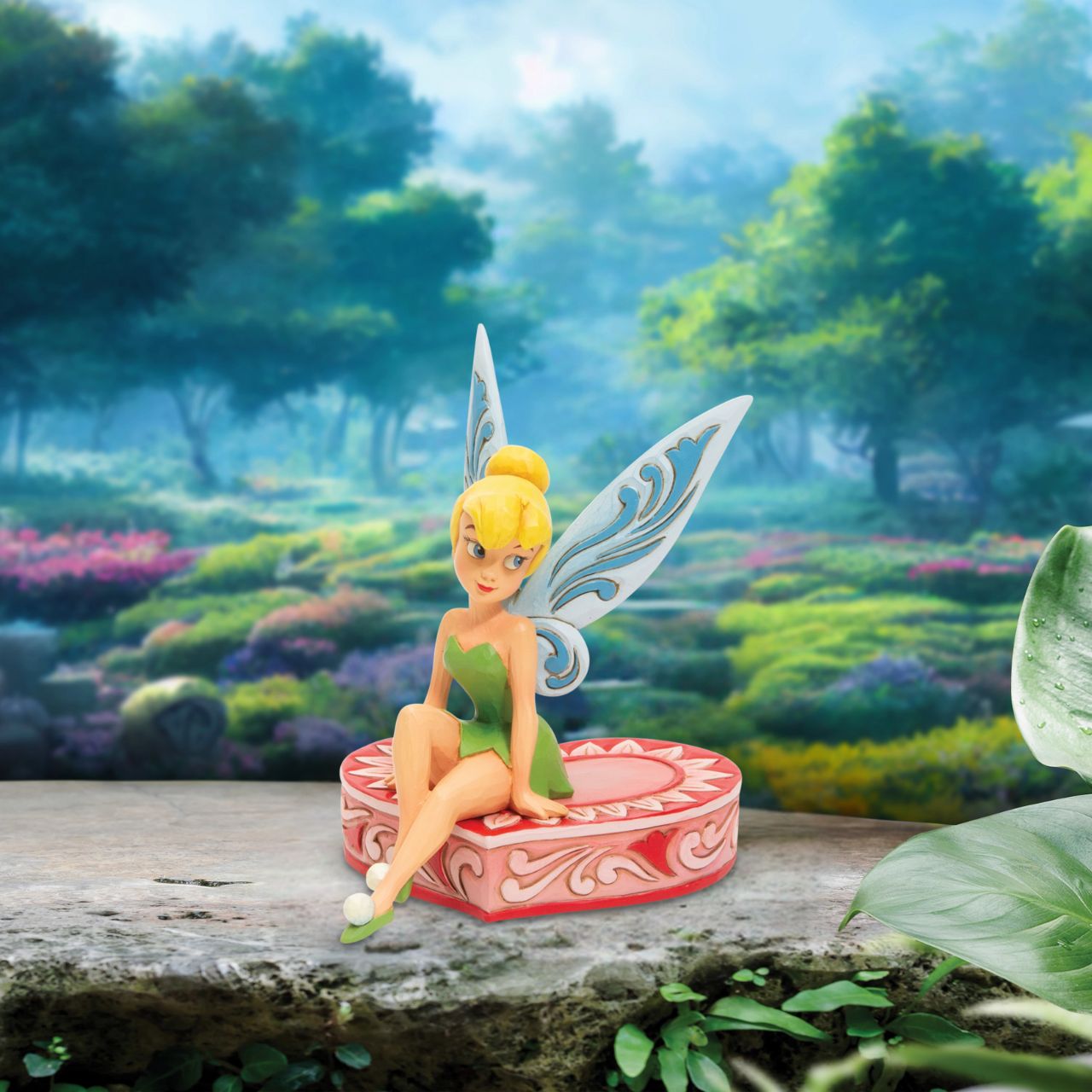This fairy is sweeter than candy and sits on a heart-shaped box in this Jim Shore collectible. Tinkerbell, Peter Pan's sassy sidekick smiles coquettishly legs crossed daintily. With delicate rosemaling this fairy is in the love seat. Unique variations should be expected as this product is hand painted. 