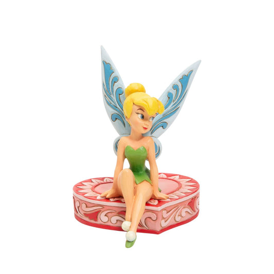 This fairy is sweeter than candy and sits on a heart-shaped box in this Jim Shore collectible. Tinkerbell, Peter Pan's sassy sidekick smiles coquettishly legs crossed daintily. With delicate rosemaling this fairy is in the love seat. Unique variations should be expected as this product is hand painted.