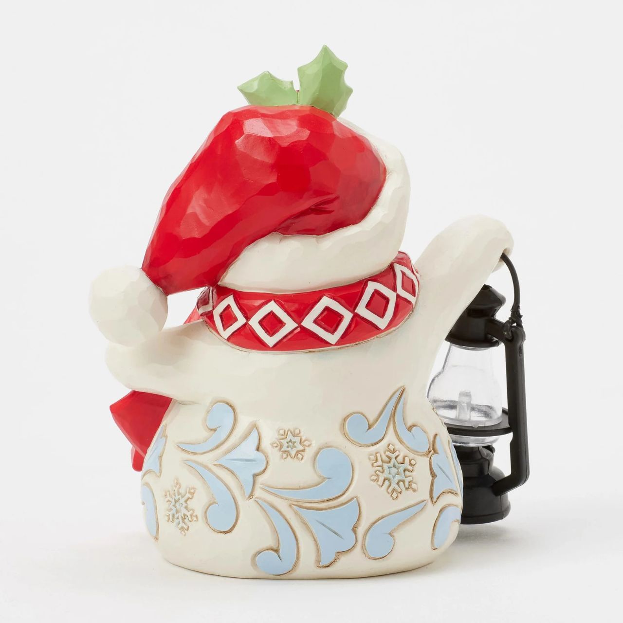 This delightful Jim Shore pint snowman carries a glowing candlelit lantern, spreading warmth and light. Dressed in a Santa hat adorned with holly, a patterned scarf, and snowflake accents, his rosy cheeks and bright smile spread Christmas cheer.