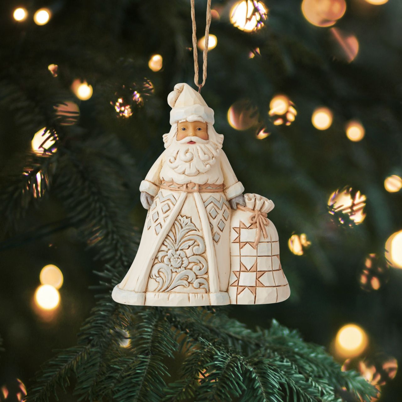 Heartwood Creek White Woodland Santa Hanging Ornament  In muted colors, this cool hued Santa brings grandeur with his deliveries. With a bag heavy with presents, this Christmas hero smiles happily from your tree, admiring the nice boys and girls as they open presents in your home.