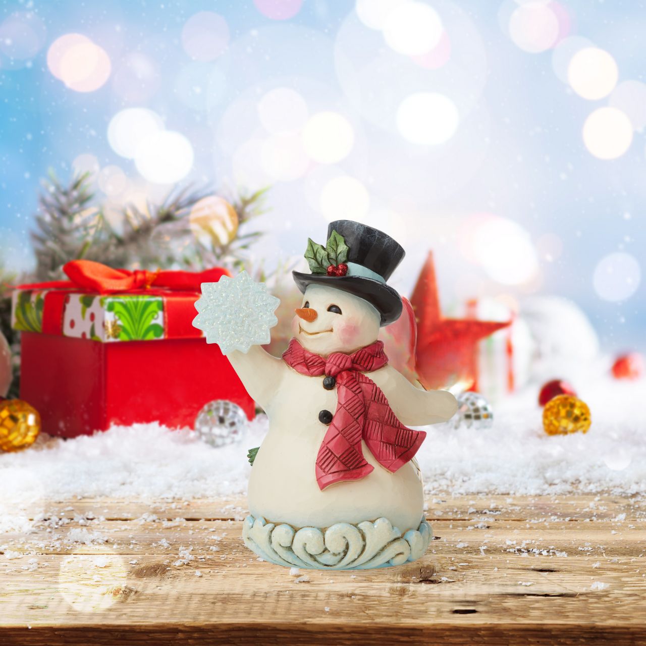 Winter Wonderland Small Snowman Figurine by Jim Shore  "Winter's Simple Joys" This happy Snowman has been designed by Jim Shore as part of his Winter Wonderland collection. Wearing a sweet top hat, he is holding an acrylic snowflake to add to the feeling of snow and ice before added embellishments of glitter are added.