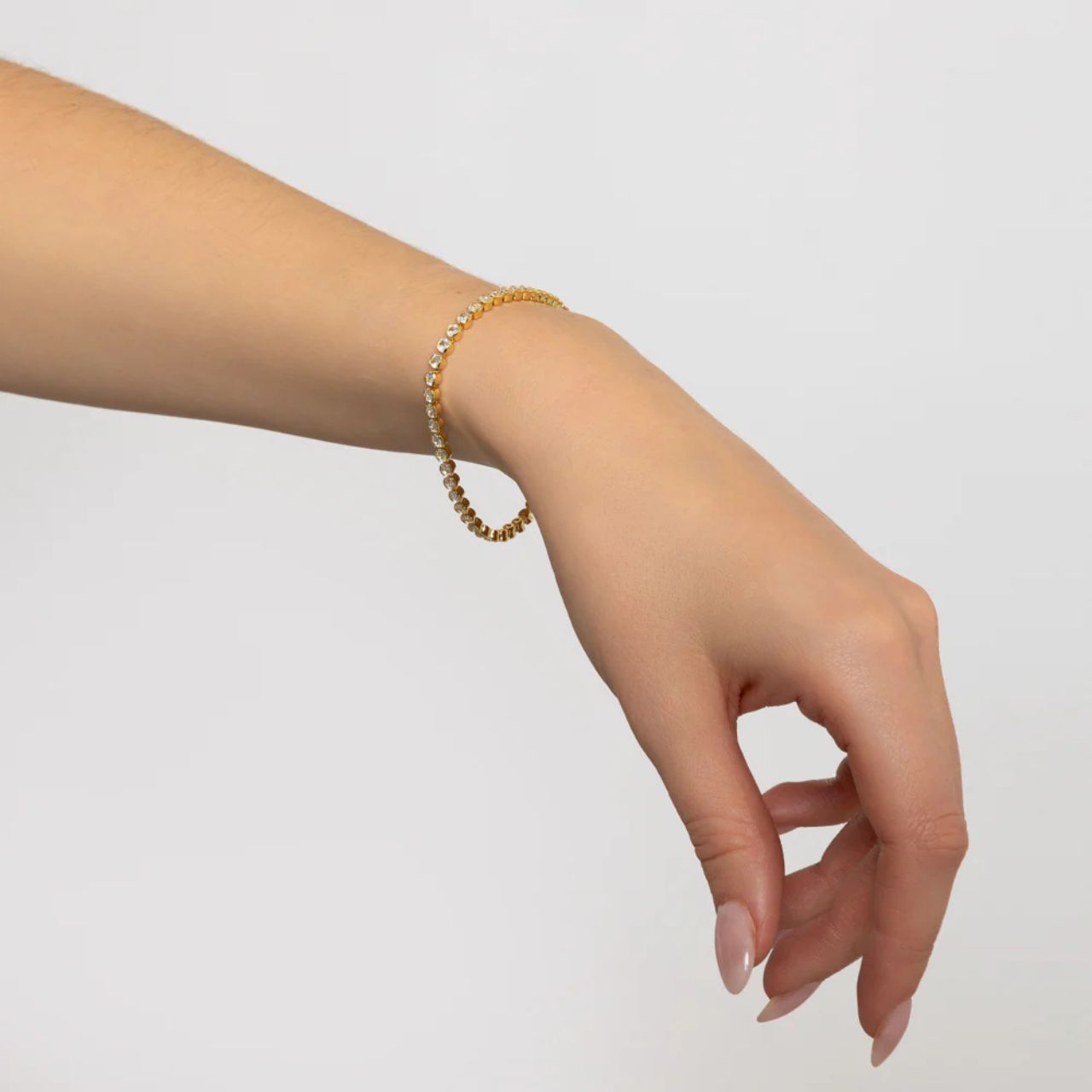 Miniature gold plated tennis bracelet. Elegant when worn alone and also ideal for layering with watch or other bracelets. Fold over clip fastening.